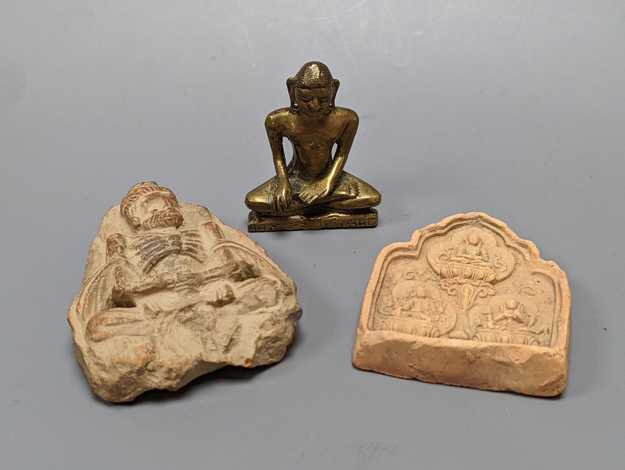 A small bronze seated figure of Buddha and two clay Buddhist tablets, largest 8 cm